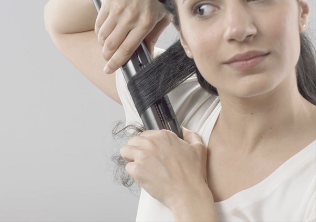 Femeie care își ondulează părul cu placa de păr Dyson Corrale