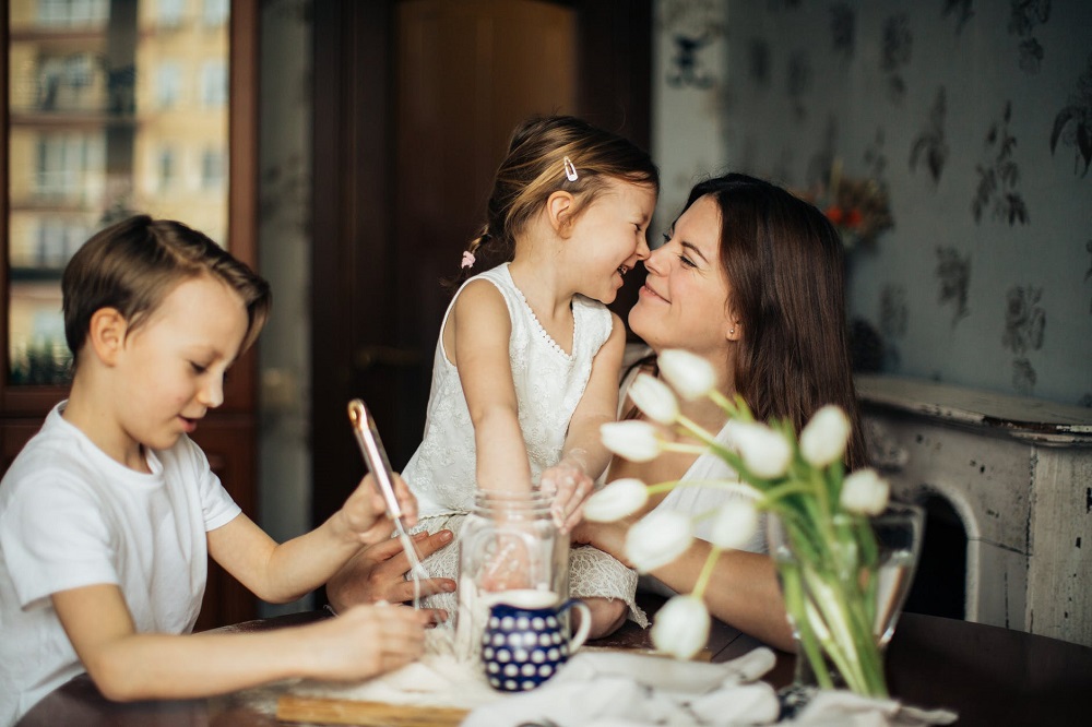 Mamă fericită, stând la masă în compania copiilor ei