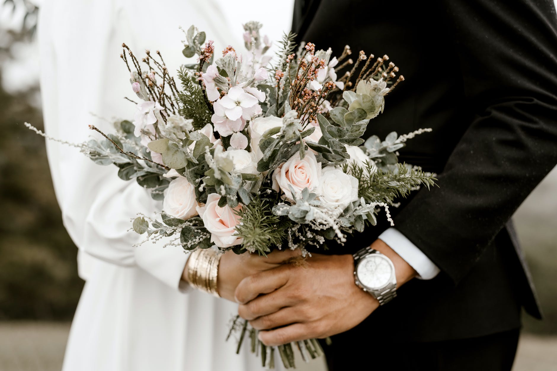 Miri care se țin de mână în ziua nunții, cu buchetul miresei în prim-plan