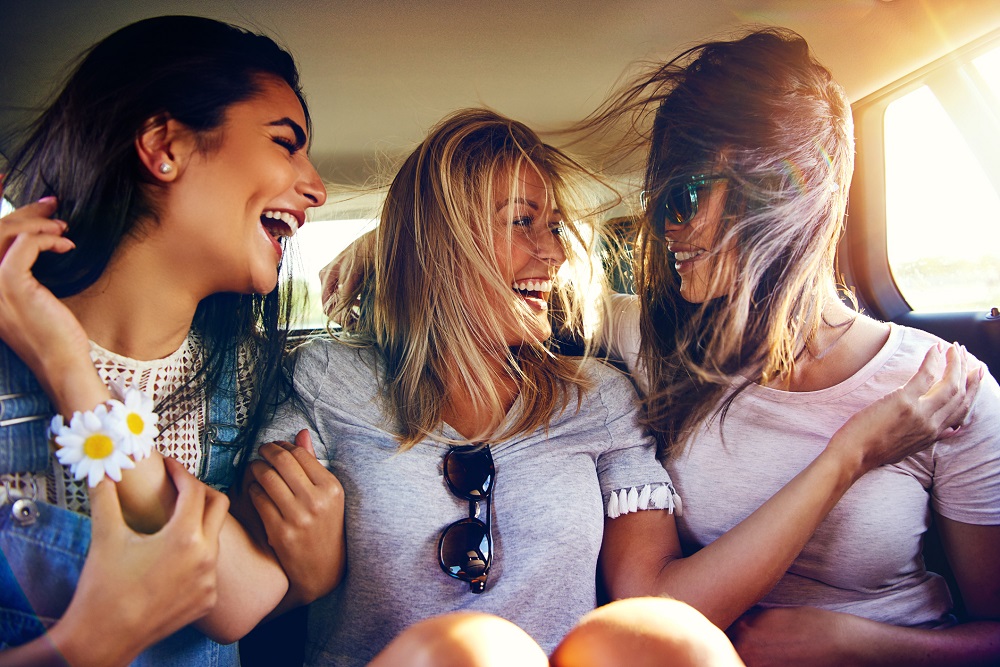 Trei prietene care glumesc și râd în timpul unei plimbări cu mașina
