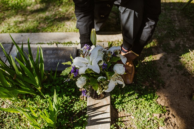 Bărbat care pune un buchet de flori pe un mormânt