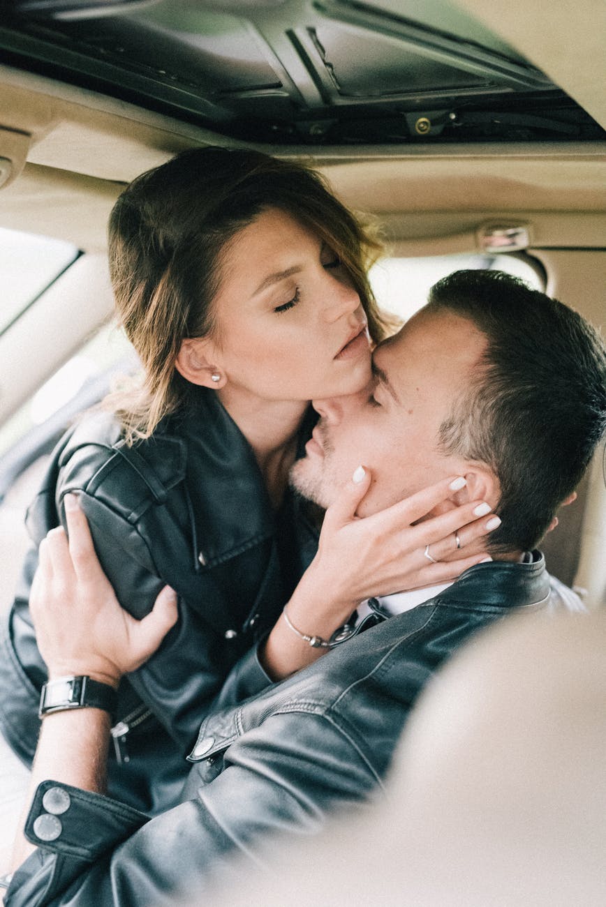 Parteneri pasionali care se îmbrățișează și se sărută în mașină