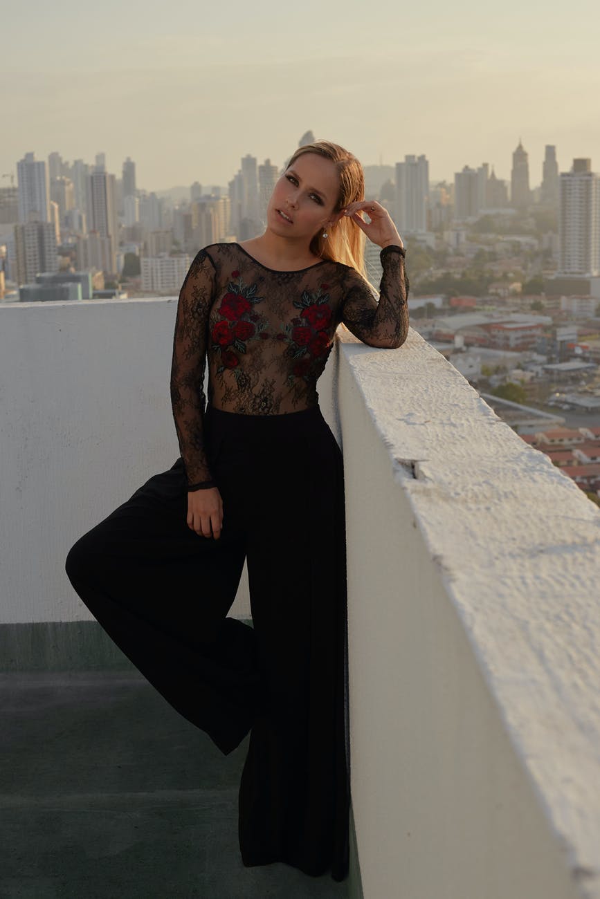 Femeie blondă, sexy și elegantă, îmbrăcată într-o bluză neagră, transparentă din dantelă.