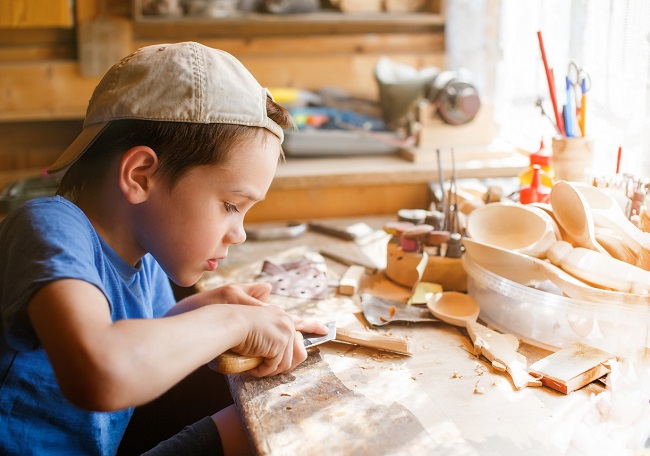 Băiețel care își construiește singur jucării din lemn