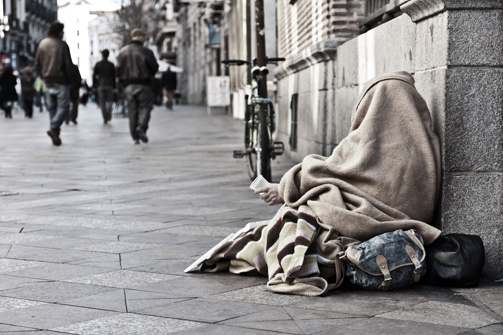 Persoană fără adăpost care doarme și cerșește pe străzi.