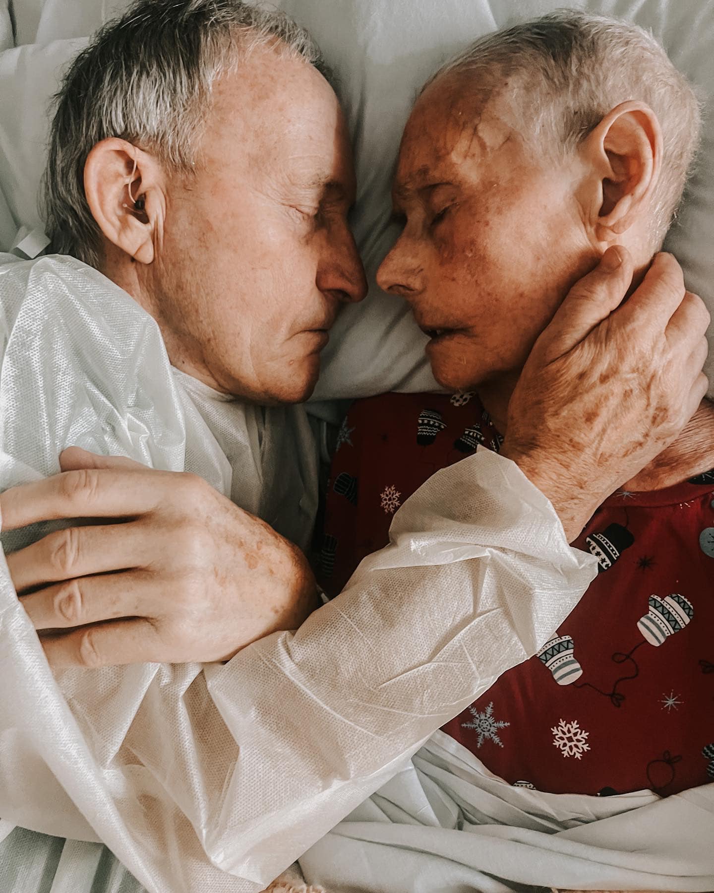 Cei doi bătrâni din poveste, stând îmbrățișați pe patul de spital, în timp ce bunicul își arată afecțiunea față de soția lui.