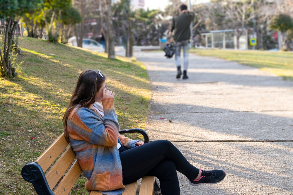 Femeie care plânge pe o bancă în parc, după ce a fost părăsită de iubit.