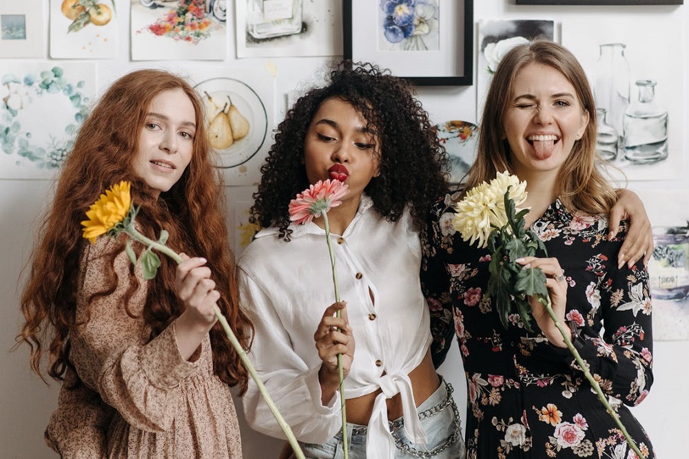 Trei femei care țin în mână flori de culori diferite: 