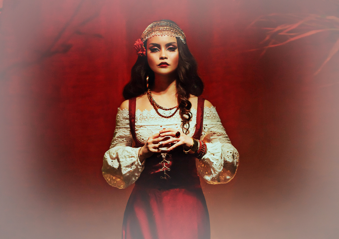 Vrăjitoare tânără, frumoasă, cu păr lung, trandafir în păr, costum traditional de ghicitoare și bijuterii de aur.