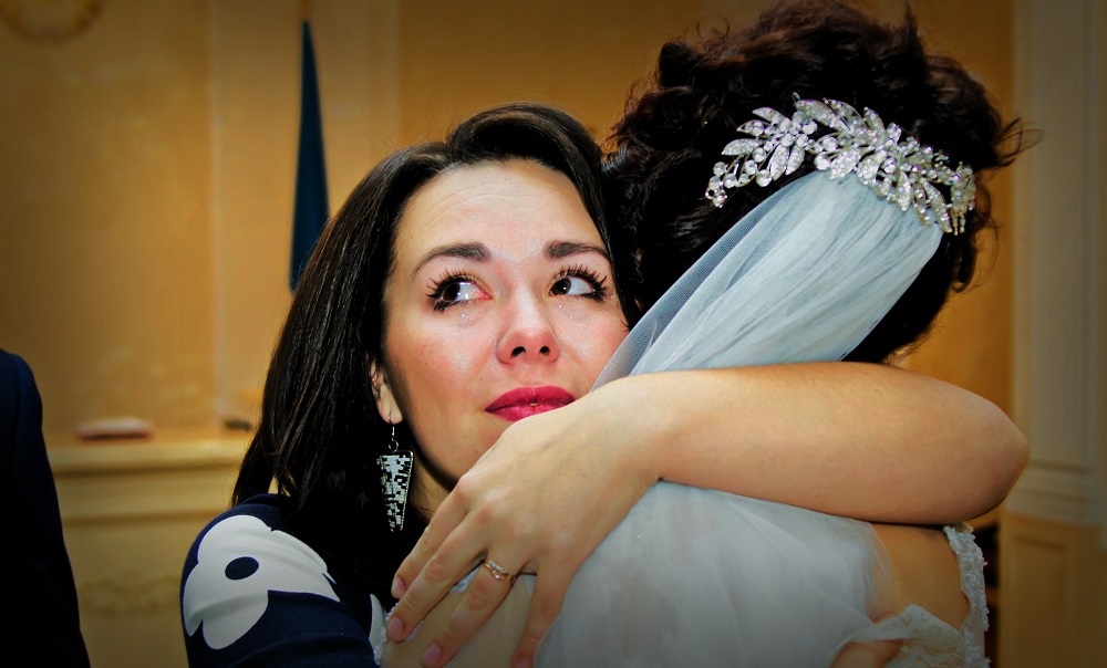 Mamă emoționată care își îmbrățișează fiica în ziua nunții sale.