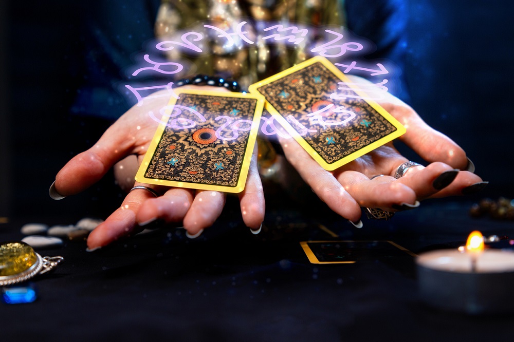 Persoană care ține în mână două cărți de Tarot