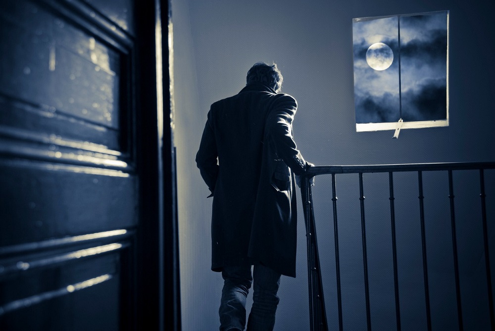 Bărbat care coboară scările unui imobil în timpul nopții, pe întuneric.