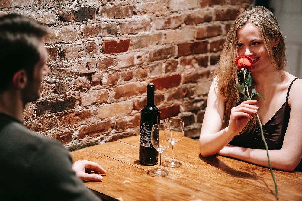 Femeie care a primit un trandafir de la partenerul său, în timpul unei cine romantice.
