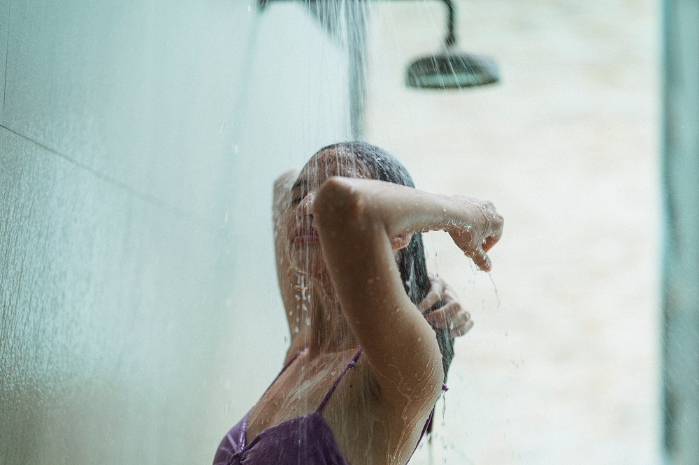 Femeie în costum de baie mov, în timp ce își face duș.
