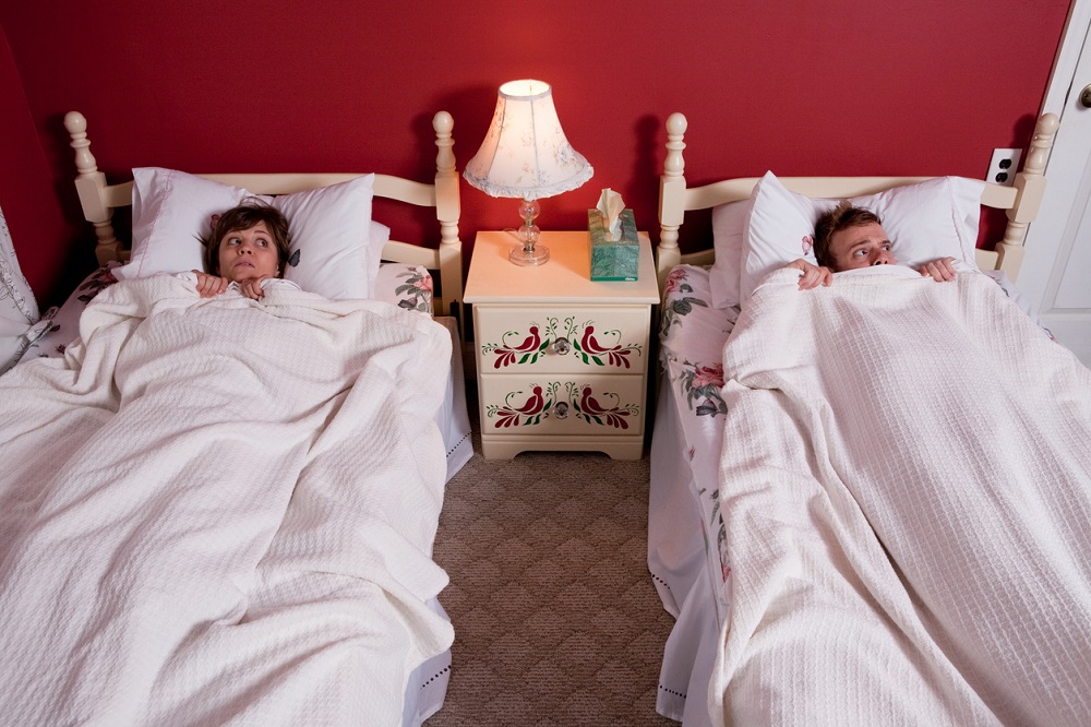 Parteneri speriați care dorm în paturi separate, dar în același dormitor.