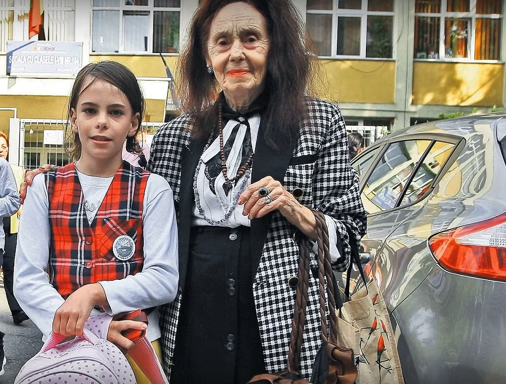 Adriana Iliescu în fața școlii alături de fiica ei, Eliza Iliescu, care este îmbrăcată în uniformă.