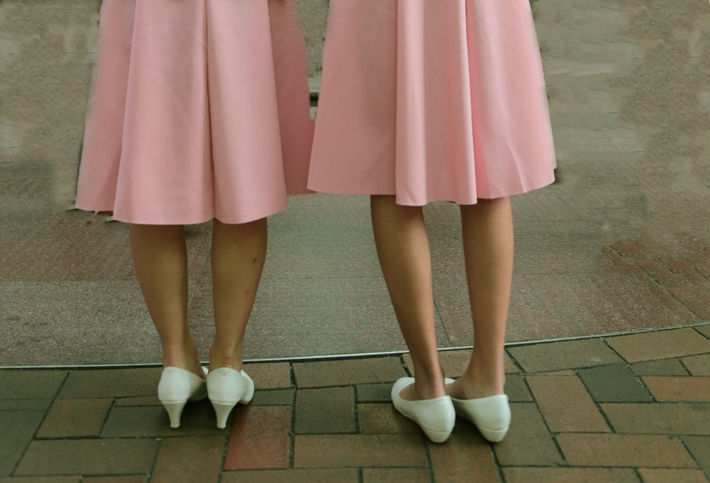 Două femei cu încălțăminte albă, una poartă pantofi cu toc și cealaltă balerini.