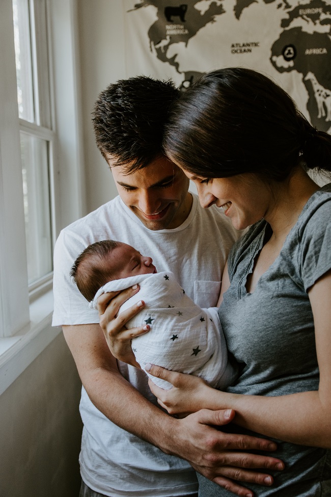 Părinți fericiți care își strâng nou-născutul în brațe.