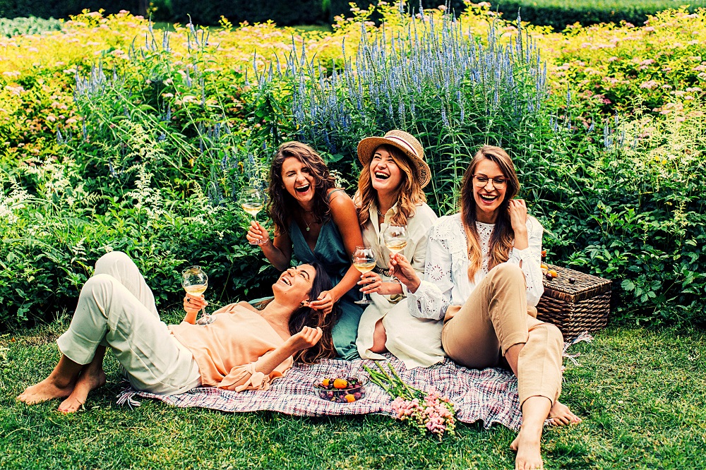 Patru femei care se distrează împreună și râd la un picnic.