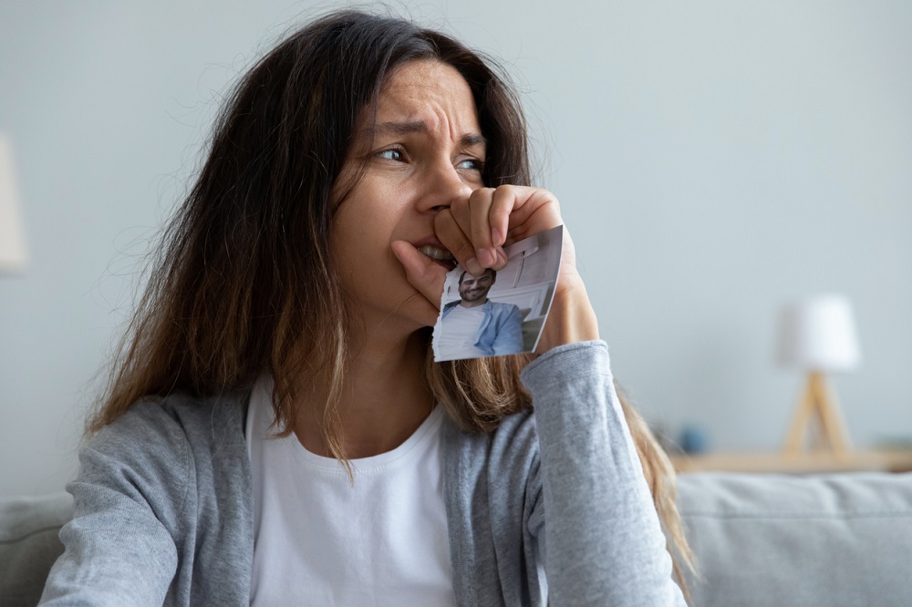 Femeie care plânge cu fotografia fostului partener în mână