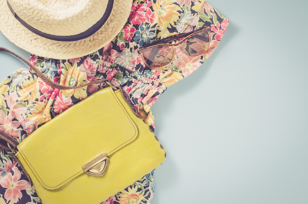 Accesorii potrivite pentru vară: rochie cu imprimeu floral, pălărie, ochelari de soare, poșetă colorată
