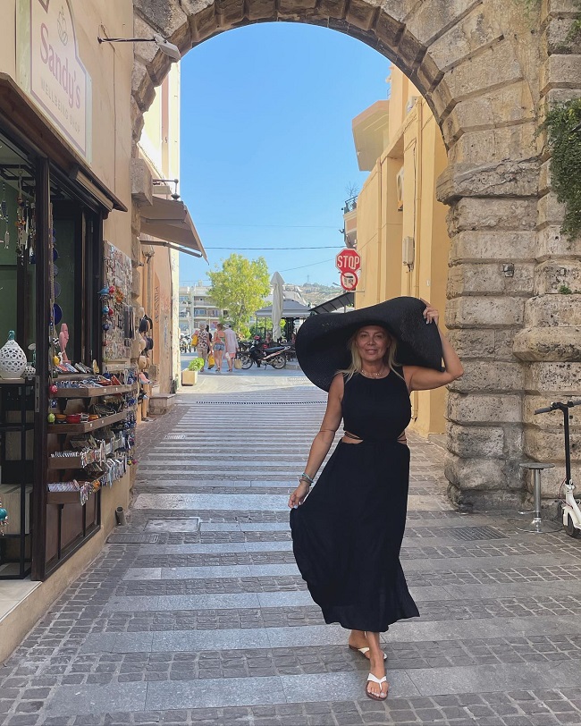Dana Săvuică în vacanță, într-o rochie neagră și cu pălătie pe cap.