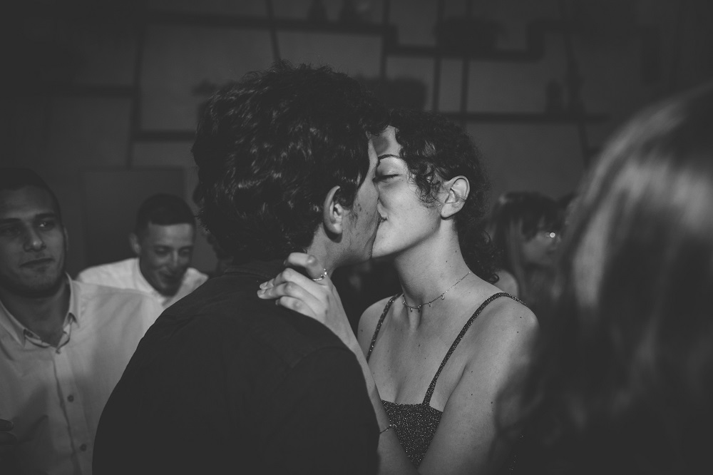 Imagine alb-negru cu o femeie care își sărută partenerul în public.