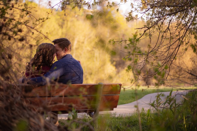 Îndrăgostiți care se sărută pe o bancă în parc.