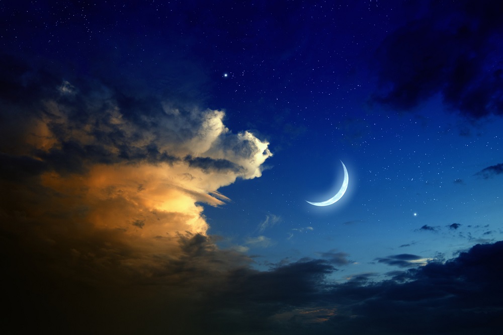 Ilustrație Luna Nouă pe un cer înstelat și cu nori colorați.
