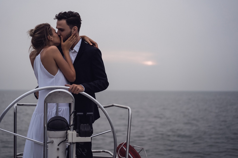 Parteneri care se sărută pe o barcă în larg.