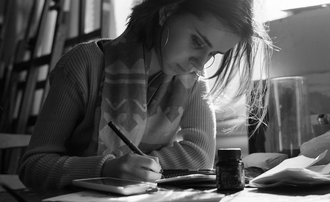 Imagine alb-negru cu o femeie care desenează sau scrie.