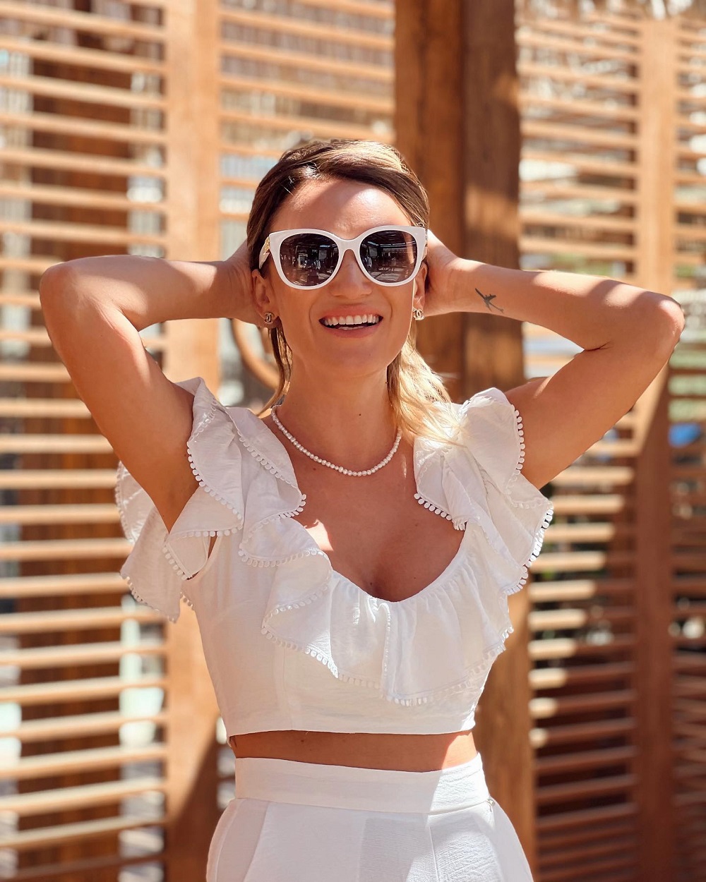 Carmen Negoiță în vacanță, purtând un compleu alb și ochelari de soare.