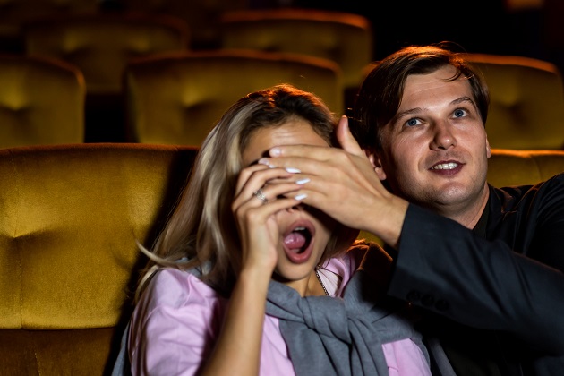 Bărbat care ocoperă ochii partenerei, astfel încât ea să nu mai vadă imaginile violente din film.