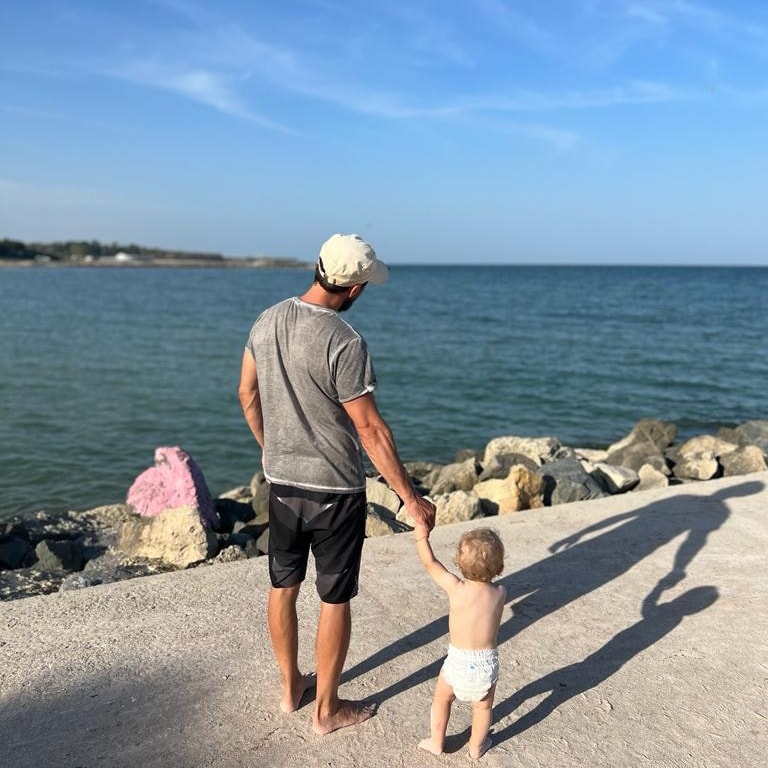 Dani Oțil privește marea, în timp ce îl ține de mână pe fiul său