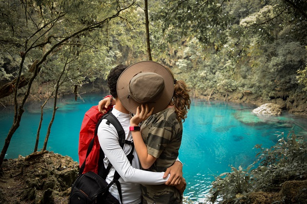 Parteneri în vacanță care se sărută și se ascund în spatele unei pălării.