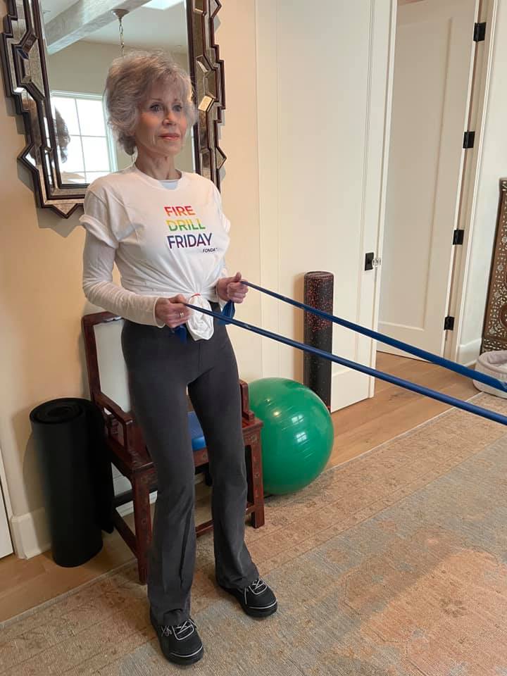 Actrița Jane Fonda, făcând sport și purtând tricoul cu numele asociației din care face parte.