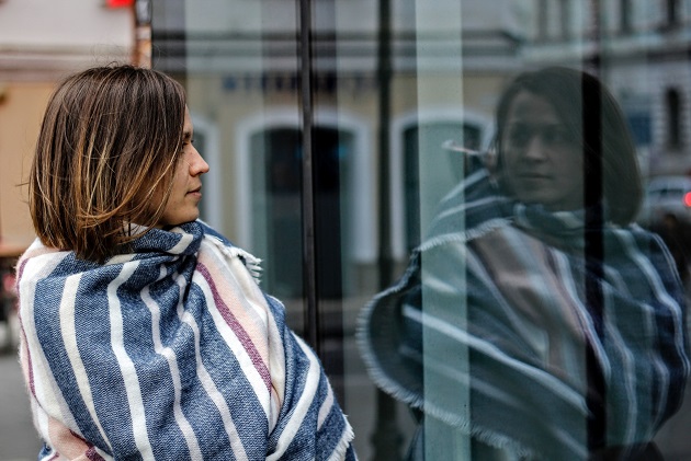 Femeie care își privește imaginea reflectată într-un geam.