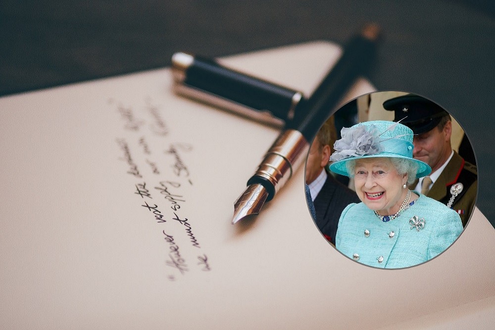 Imagine cu un stilou așezat pe o scrisoare, peste care este atașată o fotografie cu Regina Elisabeta a II-a.