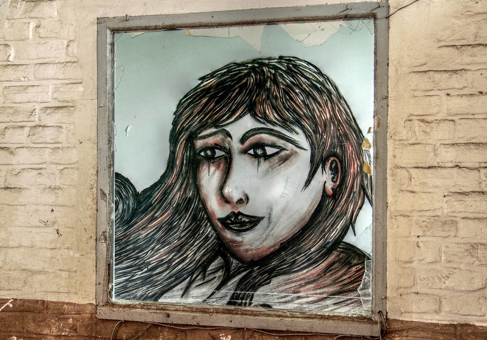 Fereastră transformată în portretul în creion al unei femei triste, cu ochii înlăcrimați.