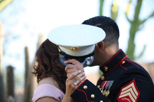 Militar marin care se sărută cu o femeie pe care o ascunde sub șapca sa.