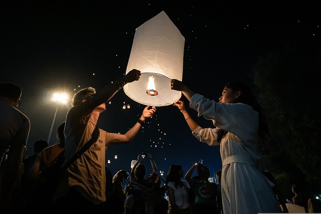 Parteneri care lansează împreună un lampion spre cer.