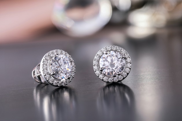 Cercei din argint cu diamant mare în centru și alte diamante mici pe margine.