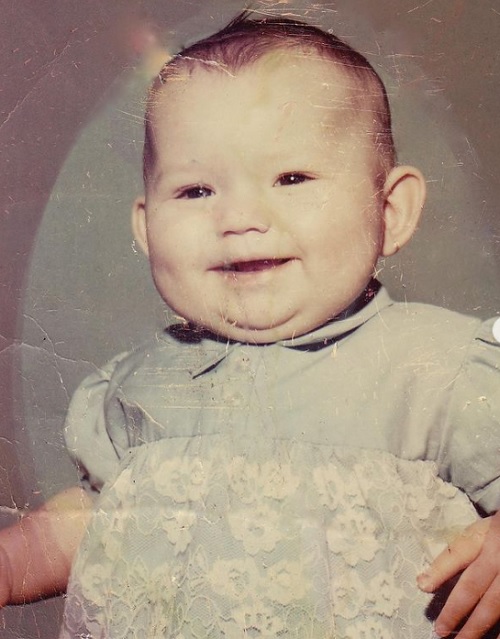 Shania Twain într-o fotografie de când era bebeluș, în timp ce purta o rochie cu flori din dantelă