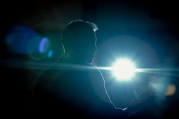 Bărbat care vorbește în public, în timp ce se află în lumina reflectoarelor.