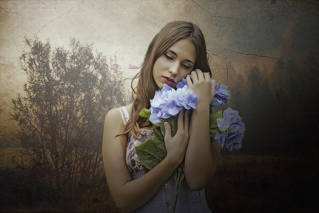 Femeie tristă în rochie cu bretele, în timp ce strânge în brațe un buchet de flori