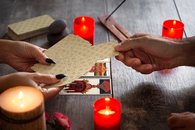 Persoană care alege o carte de Tarot din mâna ghicitoarei.