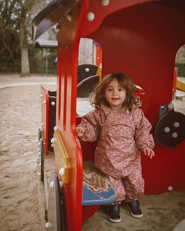 Lia, fiica Danei Rogoz, în parc, îmbrăcată într-o salopetă roz cu flori albe