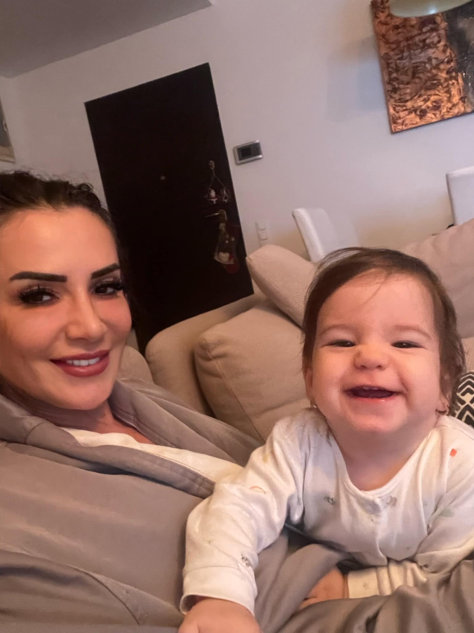 Mara Bănică și fiica ei, zâmbitoare în timp ce stau acasă pe canapea