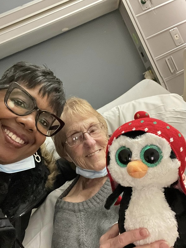 Vivian Robinson alături de Kathy Pfeiffer care stă pe patul de spital și ține în mână un pinguin de pluș