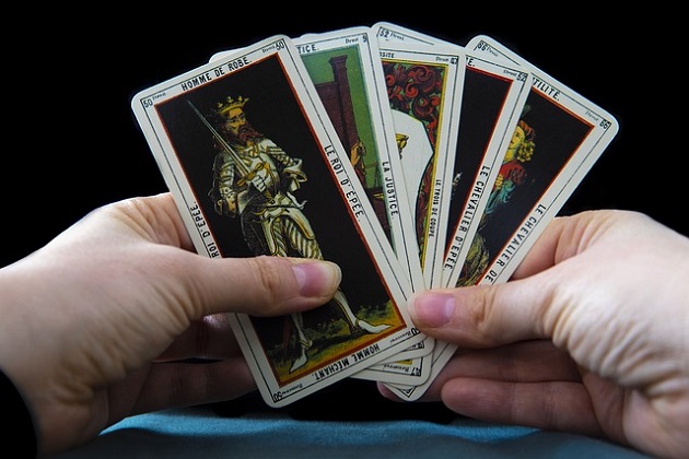 Persoană care ține în mână cinci cărți de Tarot